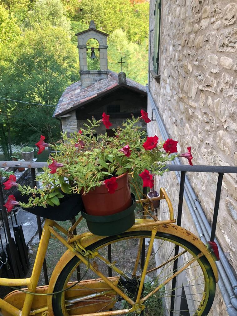 Una bicicletta gialla con i fiori, davanti alla chiesetta